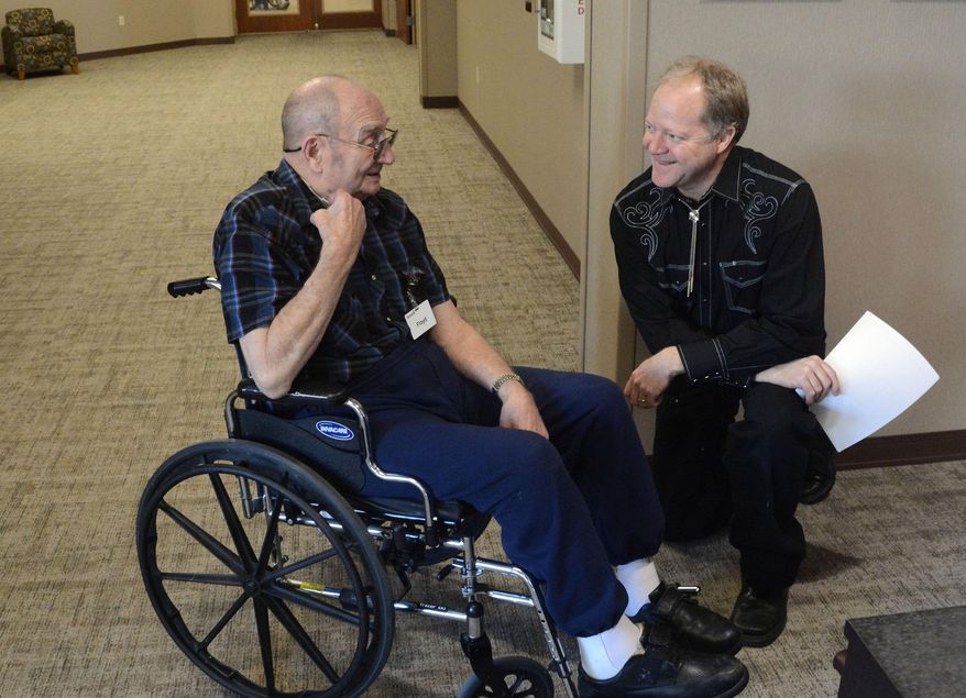 In this Dec. 3, 2015 photo, Floyd Beukelman, left, an 87-year-old resident of the Avera Prince of Peace retirement community in Sioux Falls, S.D., chats with Darrel Fickbohm before Fickbohm narrates Beukelman’s memoirs to music. The program pairs seniors’ memories with a performance by the Dakota Wind Quintent as part of the Music As Medicine program. (AP Photo/Dirk Lammers)