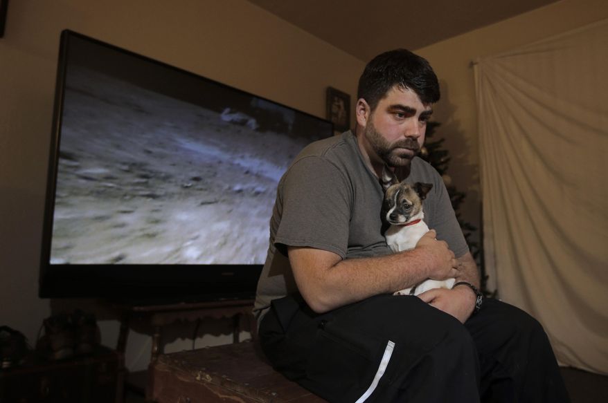 In this photo taken Thursday, Dec. 17, 2015, Josh Redmyer, a former Marine who served three tours in Iraq, poses with Milo, who he calls his "therapy dog," in Oroville, Calif. Redmyer, who was diagnosed with Post-Traumatic Stress Disorder in 2009, received a less-than-honorable discharge in 2012. He is among the thousands of veterans who cannot receive veterans health benefits because of a less-than-honorable discharge. Redmyer turns to Milo, who is a birthday present from his roommate, when he becomes despondent. (AP Photo/Rich Pedroncelli)