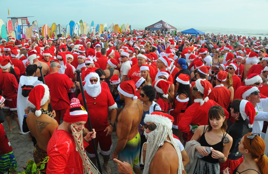 More than 6000 people showed up to watch hundreds of surfing Santas take to the waves in Cocoa Beach, Fla., Thursday, Dec. 24, 2015, at the end of Minutemen Causeway for the 7th Surfing Santas of Cocoa Beach. The event raises money for Grind for Life. The event has grown since George Trosset and his son George and daughter-in-law Britteny went surfing in Santa, snowman and elf costumes seven years ago. (Malcolm Denemark/Florida Today via AP)