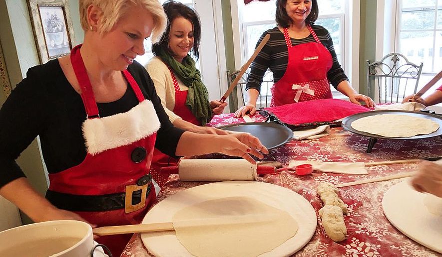 ADVANCE FOR THE WEEKEND OF DEC. 25 - In this Wednesday, Dec. 16, 2015 photo, Gerri Thorsgard, from left, Stacy Baumgart and Theresa Hendricks work to roll and cook sheets of lefse in Bemidji, Minn. Thorsgard recruited her mother-in-law to teach her and a group of friends to make lefse. That was 12 years ago. The group still meets a few times each year to practice. (John Enger/Minnesota Public Radio via AP) MANDATORY CREDIT