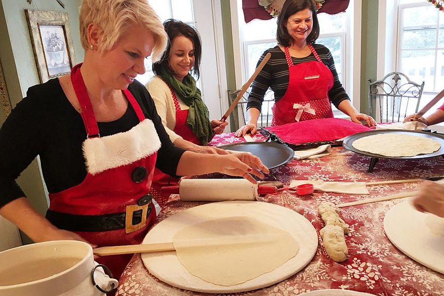 ADVANCE FOR THE WEEKEND OF DEC. 25 - In this Wednesday, Dec. 16, 2015 photo, Gerri Thorsgard, from left, Stacy Baumgart and Theresa Hendricks work to roll and cook sheets of lefse in Bemidji, Minn. Thorsgard recruited her mother-in-law to teach her and a group of friends to make lefse. That was 12 years ago. The group still meets a few times each year to practice. (John Enger/Minnesota Public Radio via AP) MANDATORY CREDIT