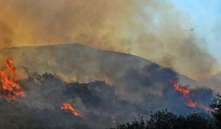 A Santa Barbara County Air Support helicopter makes a water drop while working a Solimar wildfire in Ventura County, Calif., on Saturday, Dec. 26, 2015. The fire, which began on Christmas night, has charred more than 1,200 acres. (Mike Eliason/Santa Barbara County Fire Dept. via AP)