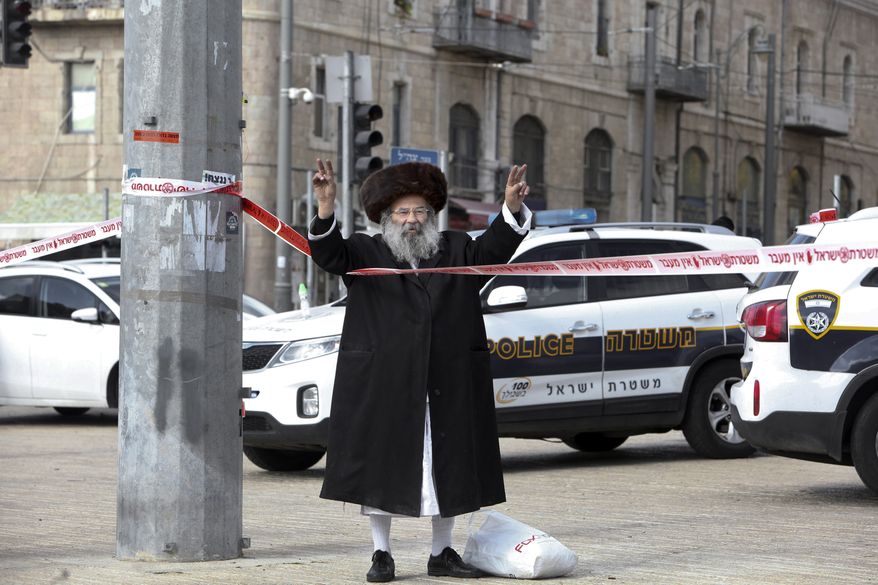 An ultra Orthodox Jew flashes victory signs at the scene of an alleged stabbing attack in Jerusalem Saturday, Dec. 26, 2015. According to a police spokeswoman, policemen approached a man who drew their suspicions just outside the Old City for following a pair of Jewish worshippers. Then he pulled out a knife and tried to stab one of them, officers opened fire and killed the assailant. (AP Photo/Mahmoud Illean)