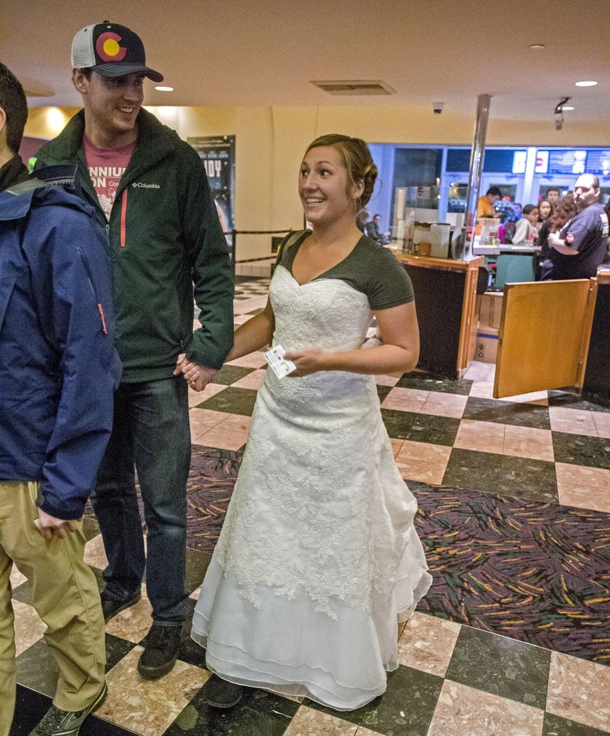 Kelsey and James Beil stand in the lobby of AMC Lakewood Mall 12 movie theater to see the latest Star Wars installment, Dec. 19, 2015. She's wearing her wedding dress and a Star Wars tee shirt to keep her promise regarding a Facebook fund-raising challenge. (Peter Haley/The News Tribune via AP)
