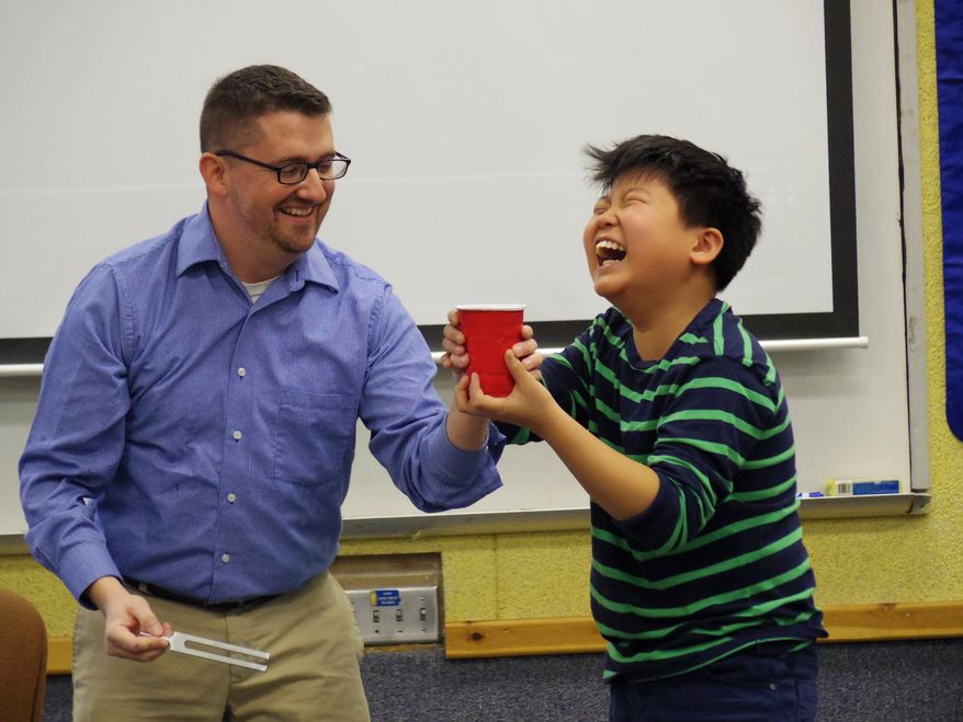 ADVANCE FOR THE WEEKEND OF DEC. 26 - In this Wednesday, Dec. 16, 2015 photo, Horizon Middle School teacher Michael Heuertz, who will be deployed in January to the Middle East, shares a laugh with sixth-grader Seth Choi during a lesson on sound vibration at the school in Kearney, Neb. (Josh Moody/The Daily Hub via AP) MANDATORY CREDIT
