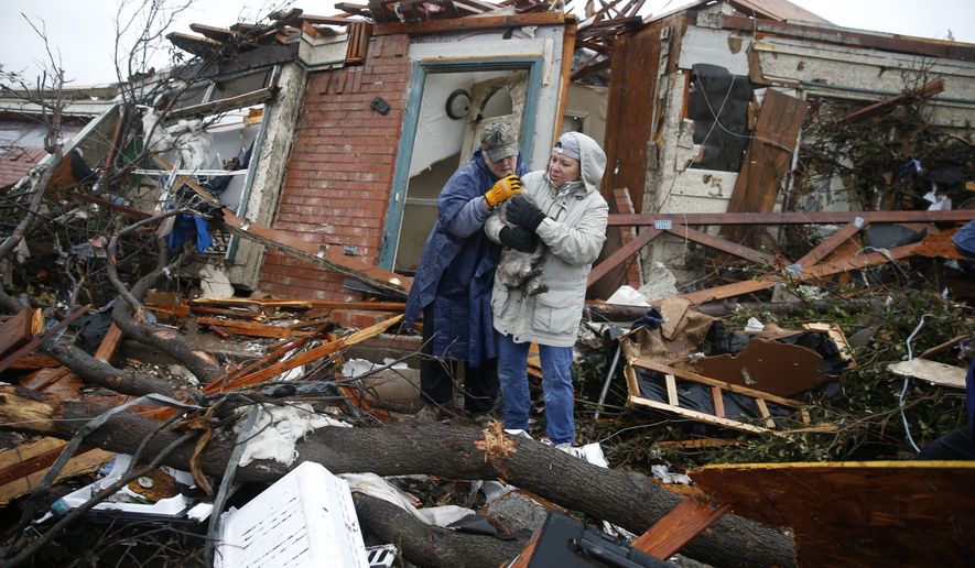 Pam Russell, left, and Linda Hart rescue Pam's cat, Larue, from Russell's house a day after a tornado hit on Delta Drive in Rowlett, Texas, Sunday, Dec. 27, 2015. At least 11 people died and dozens were injured in apparently strong tornadoes that swept through the Dallas area and caused substantial damage this weekend. (Nathan Hunsinger/The Dallas Morning News via AP)