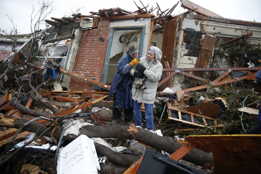 Pam Russell, left, and Linda Hart rescue Pam's cat, Larue, from Russell's house a day after a tornado hit on Delta Drive in Rowlett, Texas, Sunday, Dec. 27, 2015. At least 11 people died and dozens were injured in apparently strong tornadoes that swept through the Dallas area and caused substantial damage this weekend. (Nathan Hunsinger/The Dallas Morning News via AP)