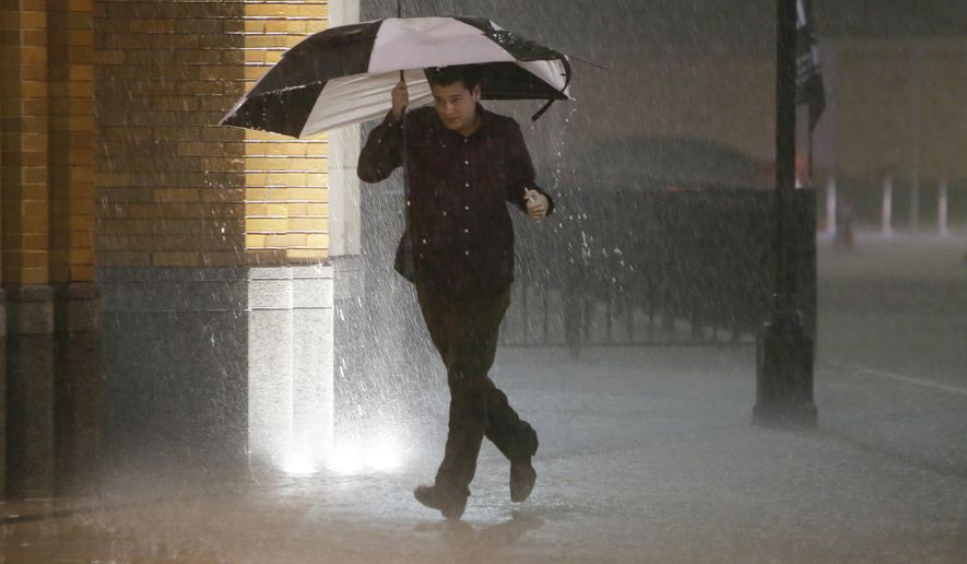 A man runs as sirens sound during a severe storm over downtown Dallas, Saturday, Dec. 26, 2015, in Dallas. The National Weather Service said the Dallas area was under a tornado warning Saturday. (AP Photo/LM Otero)