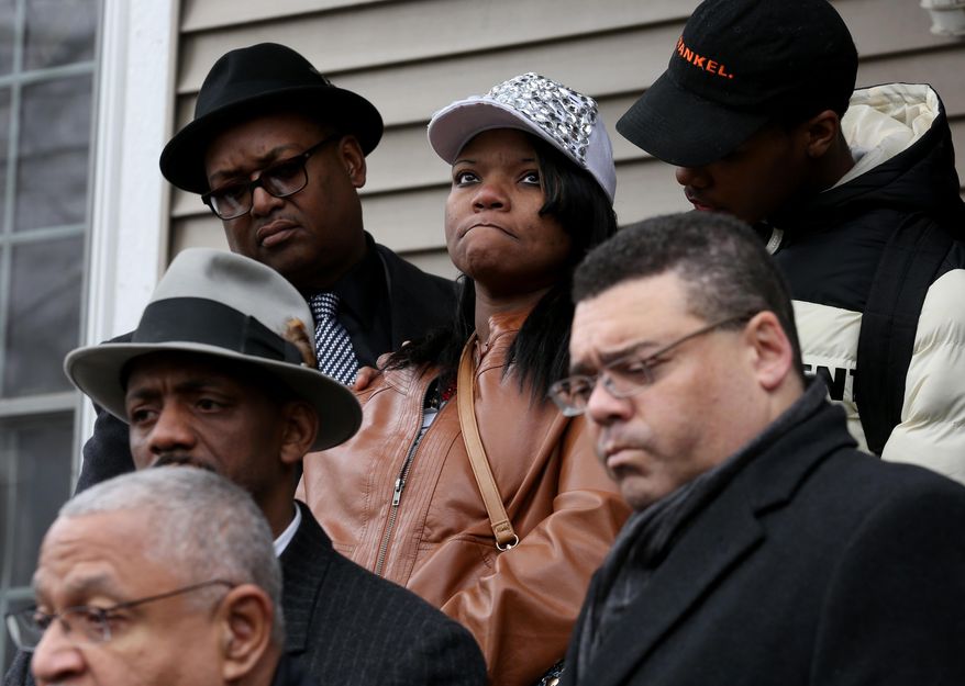 LaTarsha Jones, center, the daughter of Bettie Jones who was shot and killed by Chicago Police, is surrounded by friends and family in front of Jones' home in Chicago on Sunday, Dec. 27, 2015. Attorneys Larry Rogers, Sr., bottom left, and Sam Adam, Jr., bottom right, stand with family members. Grieving relatives and friends of Bettie Jones and a man shot and killed by Chicago police said Sunday that the city's law enforcement officers had failed its residents. (Nancy Stone/Chicago Tribune via AP)