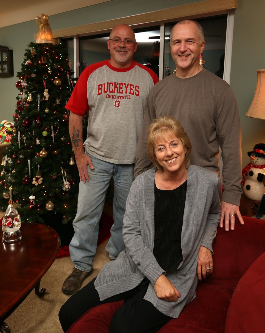 Bob Gondor, left, joins Randy Resh and his wife Traci Grimm at the Resh home on Tuesday, Dec. 22, 2015, in Garfield Heights, Ohio. The two men who say they were wrongfully imprisoned for 16 years for an Ohio woman's 1988 slaying filed for monetary compensation. (Michael Chritton/Akron Beacon Journal via AP)