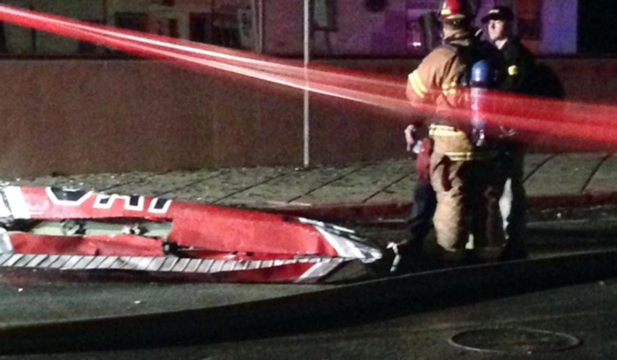 Firefighters stand near a piece of wreckage after a small plane slammed into a commercial building in downtown Anchorage, Alaska, early Tuesday, Dec. 29, 2015. Authorities say at least one person aboard died. Assistant Fire Chief Alex Boyd said there were no injuries on the ground.(AP Photo/Rachel D'Oro)