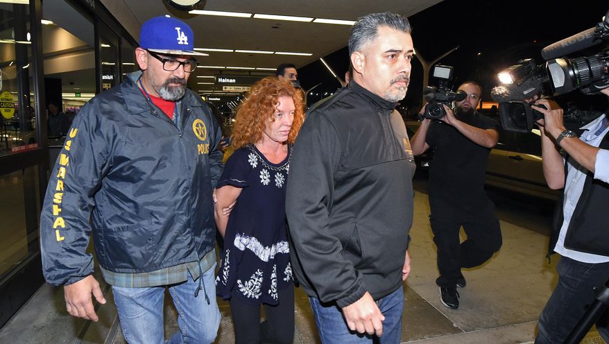 Tonya Couch, center, is taken by authorities to a waiting car after arriving at Los Angeles International Airport, Thursday, Dec. 31, 2015, in Los Angeles. Authorities said she and her son, Texas teenager Ethan Couch, who was sentenced to probation after using an "affluenza" defense for a 2013 wreck in Texas, fled to Mexico together in November as prosecutors investigated whether he had violated his probation. Both were taken into custody Monday, Dec. 28, after authorities said a phone call for pizza led to their capture in the resort city of Puerto Vallarta. (AP Photo/Mark J. Terrill)