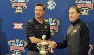 Oklahoma State head coach Mike Gundy, left, and Mississippi head coach Hugh Freeze pose with the trophy during a press conference for the Sugar Bow NCAA college football game, Thursday, Dec. 31, 2015, in New Orleans. (Bruce Newman/The Oxford Eagle via AP)