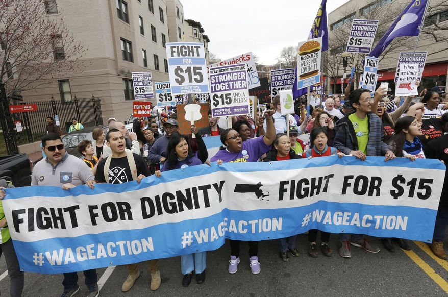 FILE - In this Tuesday, April 14, 2015 file photo, protesters, including college students, fast-food restaurant employees and other workers, display placards and chant slogans as they march in Boston. New laws taking effect on Jan. 1, 2016, will raise the minimum wage in several states, including Massachusetts. (AP Photo/Steven Senne, File)