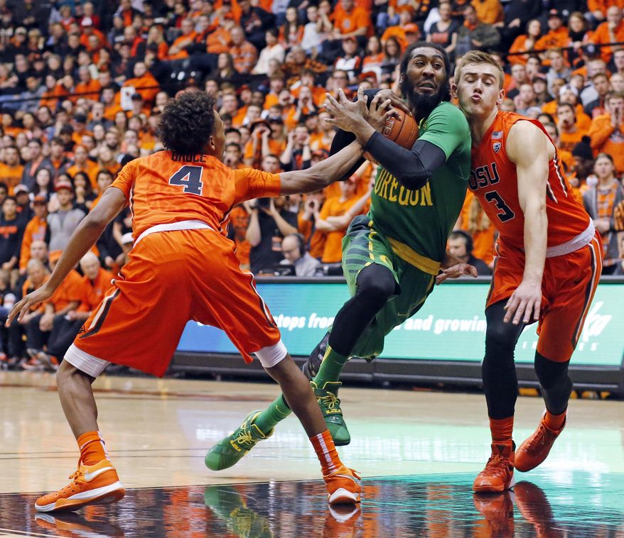 Oregon's Dwanye Benjamin, center, drives between Oregon State's Derrick Bruce, left, and Tres Tinkle, right, in the first half of an NCAA college basketball game in Corvallis, Ore., Sunday, Jan. 3, 2016. (AP Photo/Timothy J. Gonzalez)