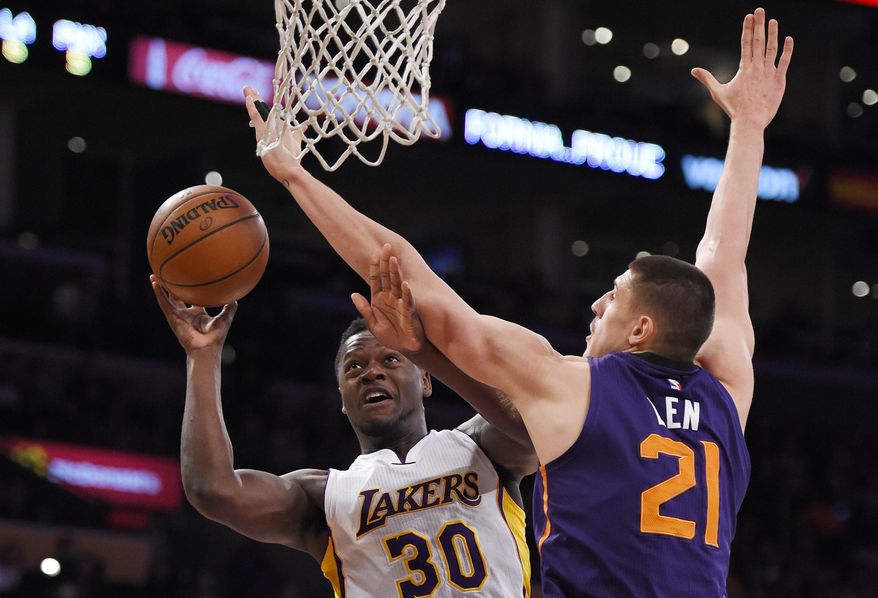 Los Angeles Lakers forward Julius Randle, left, shoots as Phoenix Suns center Alex Len, of Ukraine, defends during the first half of an NBA basketball game, Sunday, Jan. 3, 2016, in Los Angeles. (AP Photo/Mark J. Terrill)