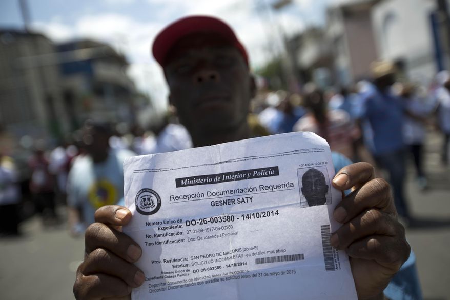 FILE - In this July 21, 2015, file photo, deported Haitian man holds up his document that confirms he turned in paperwork to apply for legal residency in the Dominican Republic during a march to the prime minister's office to protest the DR's deportation of Haitians in Port-au-Prince, Haiti. The sharply uneven situation for non-citizens stems from a 2013 ruling by the Dominican Constitutional Court in a decades-long dispute over who is entitled to citizenship. (AP Photo/Dieu Nalio Chery, File)