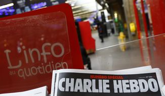 A special edition of the satirical newspaper Charlie Hebdo that marks one year after, &quot;1 an apres&quot; the attacks on it, on a newsstand Wednesday, Jan. 6, 2016 at a train station in Paris. Seventeen people died in the attacks on Charlie Hebdo on Jan. 7, 2015, and a kosher supermarket two days later. All three attackers died. (AP Photo/Francois Mori)