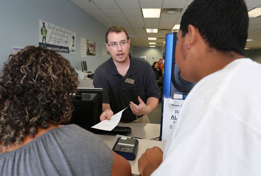FILE - In this Aug. 1, 2014 file photo, immigrant and longtime resident in the United States Rosalva Mireles, left, is processed for her permanent driver's license at a Department of Motor Vehicles office, in Denver. Colorado Democrats are decrying a Republican decision to not add funding to a program allowing immigrants to get driver's licenses regardless of their legal status. There's been high demand for the program since it launched last year. (AP Photo/Brennan Linsley, file)