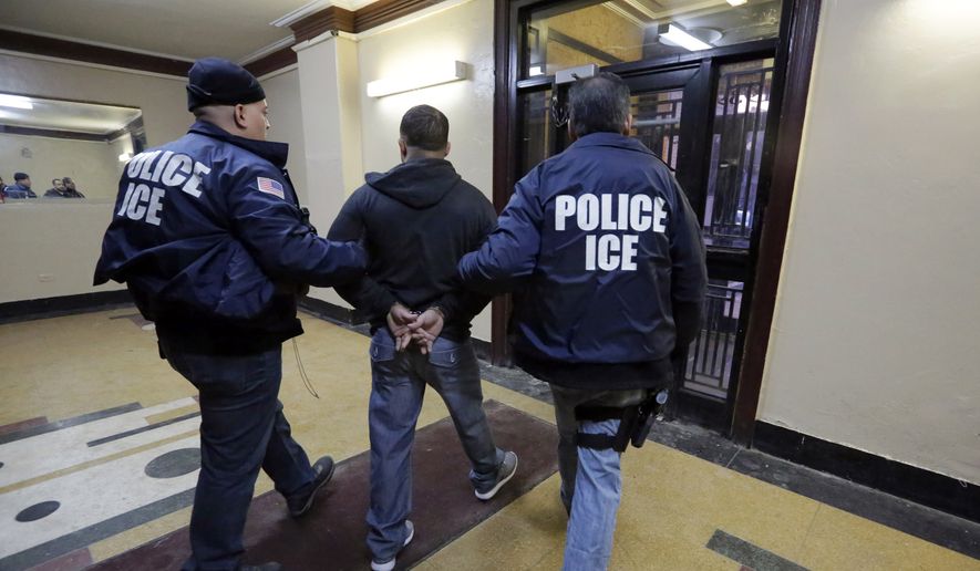 Immigration and Customs Enforcement officers escort an arrestee during a series of early-morning raids on March 3, 2015. (Associated Press) ** FILE **