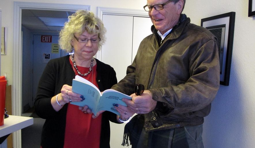 Montana Secretary of State Linda McCulloch shows Commissioner of Political Practices Jonathan Motl the location of the state's new campaign finance rules in the Montana Administrative Register on Friday, Jan. 8, 2016, in Helena, Montana. The new rules, which became effective with their publication Friday, will require more disclosure and transparency by candidates and political committees. (AP Photo/Matt Volz)
