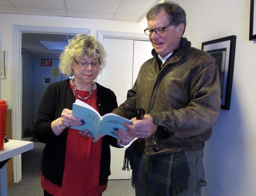 Montana Secretary of State Linda McCulloch shows Commissioner of Political Practices Jonathan Motl the location of the state's new campaign finance rules in the Montana Administrative Register on Friday, Jan. 8, 2016, in Helena, Montana. The new rules, which became effective with their publication Friday, will require more disclosure and transparency by candidates and political committees. (AP Photo/Matt Volz)