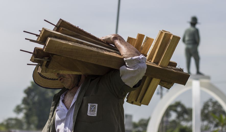 A city employee removes wooden crosses that were placed in a plaza by organizations protesting against government inaction over the alarming murder rate in San Salvador, El Salvador, on Sept. 1, 2015. (Associated Press)