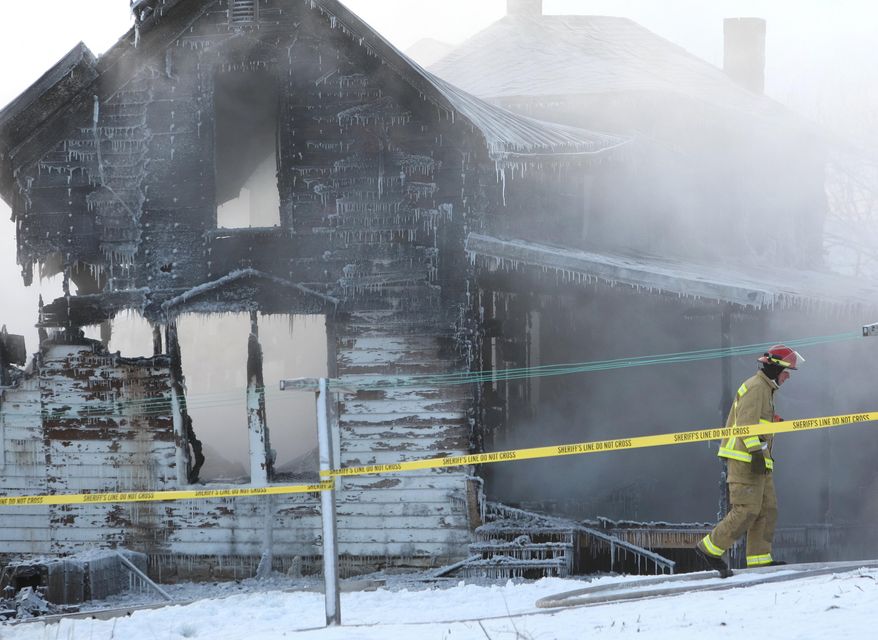 A firefighter from Harmony, Minn., walks past the smoldering remains of a fire at an Amish home north of Canton, Minn., Monday morning Jan.11, 2016. Authorities say two people are missing and two others have been injured in the fire. (Ken Klotzbach/The Rochester Post-Bulletin via AP) MANDATORY CREDIT
