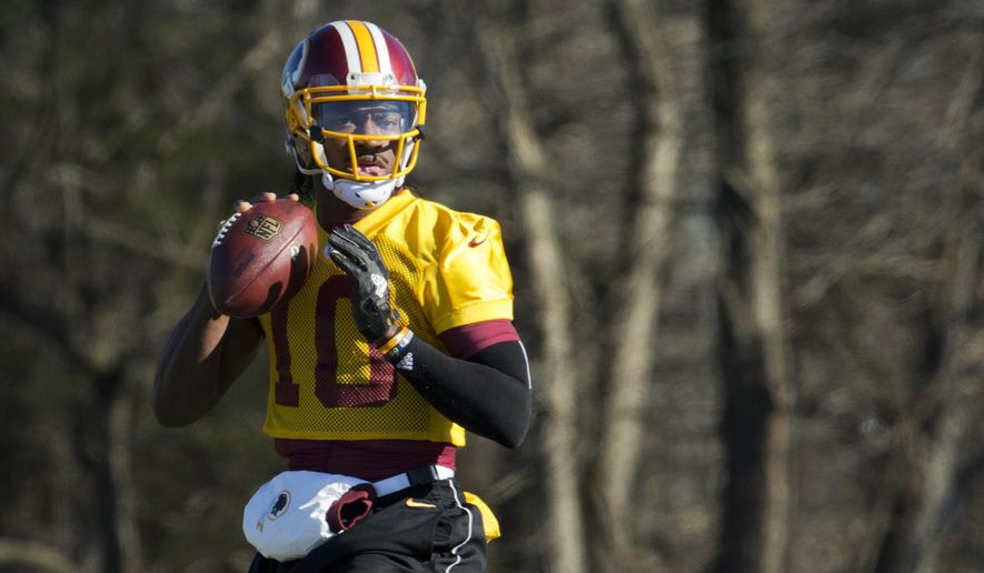 FILE - In this Jan. 6, 2016 file photo, Washington Redskins quarterback Robert Griffin III eyes the receiver during NFL football practice at Redskins Park in Ashburn, Va. Griffin has cleared out his locker at Redskins Park and is expected to be let go by the team that dealt a trove of draft picks for the right to pick him No. 2 overall in  2012. (AP Photo/Manuel Balce Ceneta, File)