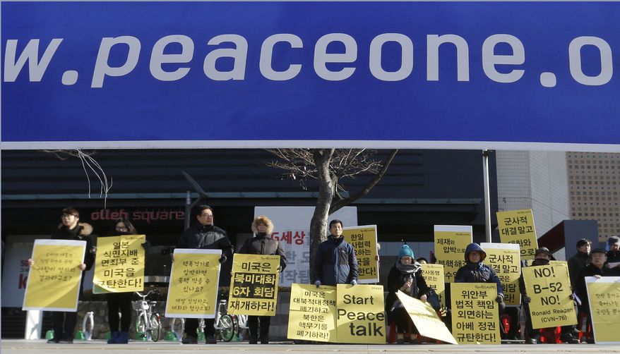 Protesters stage a rally demanding a restart of peace talks between two Koreas and six-party talks, in Seoul, South Korea, Tuesday, Jan. 12, 2016. North Korean leader Kim Jong Un looked Monday to milk his country's recent nuclear test as a propaganda victory, praising his scientists and vowing more nuclear bombs a day after the U.S. flew a powerful nuclear-capable warplane close to the North in a show of force. The placards read "Start the meeting between two Koreas and six-party talks" and "Peace instead of war." (AP Photo/Ahn Young-joon)