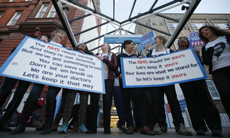 The British National Heath Service Singers, who are either doctors or nurses, perform a protest song in support of junior doctors outside Great Ormond Street Hospital for Sick Children, as a 24 hour junior doctor strike starts in London, Tuesday, Jan. 12, 2016. Thousands of junior doctors have walked off the job in England in a dispute over pay and working conditions - the first such strike in 40 years. Some 50,000 junior doctors - who represent a third of the medical workforce - are on strike for 24 hours amid government plans to change pay and work schedules. (AP Photo/Alastair Grant)