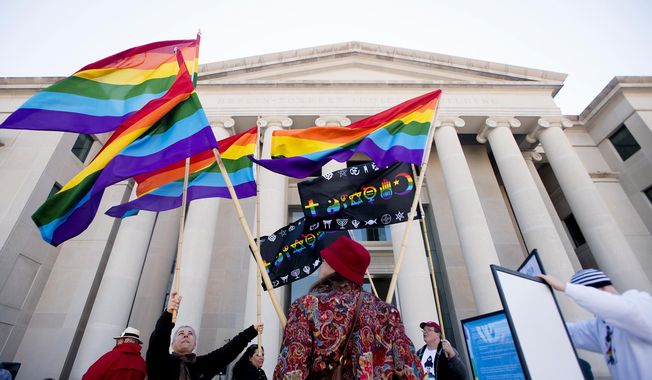 In this file photo, Minoo Vafai, left, holds rainbow flags with others during a rally against Alabama Chief Justice Roy Moore on Tuesday, Jan. 12, 2016, outside the Alabama Supreme Court building in Montgomery, Ala. Supporters of gay marriage rallied Tuesday against Moore and his opposition to same-sex marriage. (Albert Cesare /The Montgomery Advertiser via AP)  NO SALES; MANDATORY CREDIT **FILE**