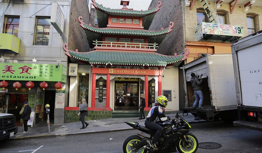 In this Wednesday, Dec. 16, 2015 photo, people make their way past a Chinatown bank in San Francisco. The best plan for tackling San Francisco’s Chinatown is no plan at all. Simply wandering the wide streets and narrow alleys will take you where you need to go.  (AP Photo/Eric Risberg)