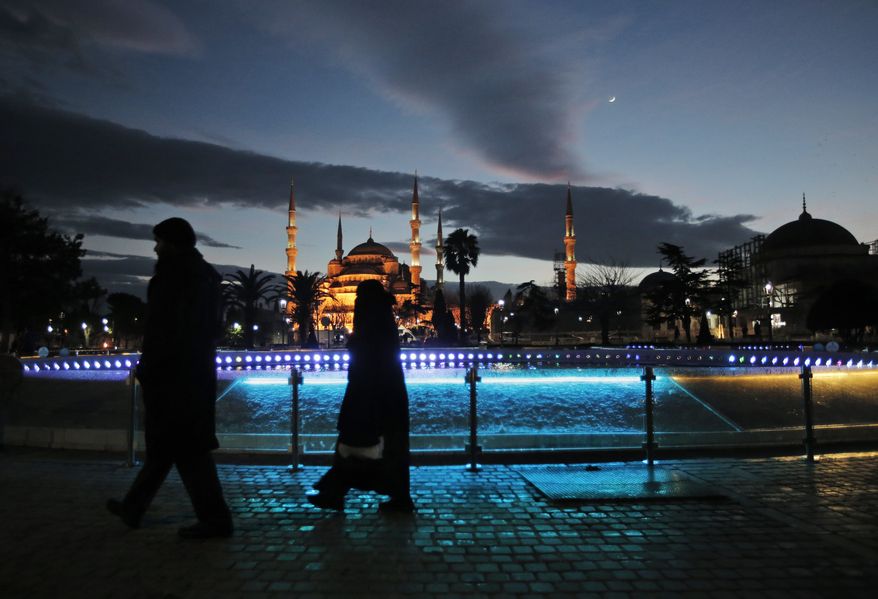 Tourists walk backdropped by the Sultan Ahmed Mosque, better known as the Blue Mosque, in the historic Sultanahmet district of Istanbul, following an explosion nearby, Tuesday, Jan. 12, 2016. The explosion killed several people and wounded 15 others Tuesday morning in the historic district of Istanbul popular with tourists. Turkish President Recep Tayyip Erdogan said a Syria-linked suicide bomber is believed to be behind the attack. (AP Photo/Lefteris Pitarakis)