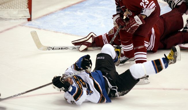 Washington Capitals left winger Alex Ovechkin, front, of Russia, shoots the puck from over his head after being checked to the ice by Phoenix Coyotes defenseman Paul Mara, center, past Coyotes goalie Brian Boucher, rear, for a goal in the third period of NHL action Monday, Jan. 16, 2006, in Glendale, Ariz. The Capitals defeated the Coyotes 6-1.(AP Photo/Paul Connors)