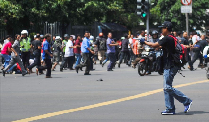 In this photo released by China's Xinhua News Agency, an unidentified man with a gun walks in the street as people run in the background on Thamrin street near Sarinah shopping mall in Jakarta, Indonesia, Thursday, Jan. 14, 2016. Suicide bombers exploded themselves in downtown Jakarta on Thursday while gunmen attacked a police post nearby, a witness told The Associated Press. Local television reported more explosions in other parts of the city. (Veri Sanovri/Xinhua via AP) NO SALES