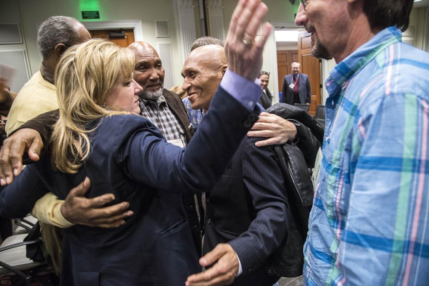 Attorney Christine Mumma gets a hug from exonerees including from left to right Willie Grimes, Larry Lamb, Joseph Sledge, Dwayne Dail and Greg Taylor following a misconduct hearing at the North Carolina State Bar in Raleigh, N.C. Thursday, Jan. 14, 2014. Mumma, an attorney known for her advocacy of the wrongly imprisoned, was admonished Thursday by a disciplinary panel for taking a water bottle from someone without their permission and having it tested for DNA. (Travis Long /The News & Observer via AP) MANDATORY CREDIT