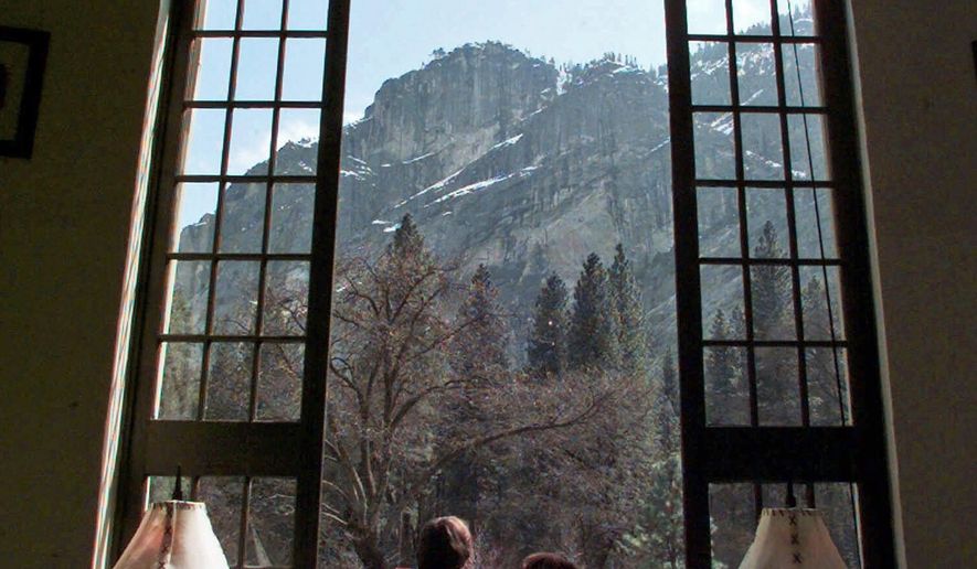 FILE - In this March 29, 1999, file photo, a couple look though a window at The Ahwahnee hotel in Yosemite, Calif. The names of iconic hotels and other facilities in the world-famous park will soon change in an ongoing battle over who owns the intellectual property, park officials said Thursday, Jan. 14, 2016. The famed Ahwahnee Hotel will become the Majestic Yosemite Hotel. (AP Photo/Paul Sakuma, File)