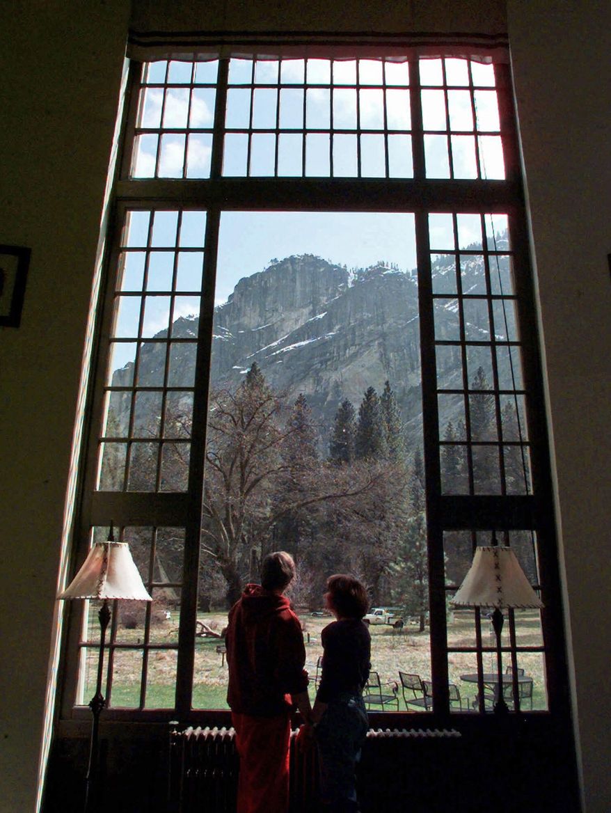 FILE - In this March 29, 1999, file photo, a couple look though a window at The Ahwahnee hotel in Yosemite, Calif. The names of iconic hotels and other facilities in the world-famous park will soon change in an ongoing battle over who owns the intellectual property, park officials said Thursday, Jan. 14, 2016. The famed Ahwahnee Hotel will become the Majestic Yosemite Hotel. (AP Photo/Paul Sakuma, File)