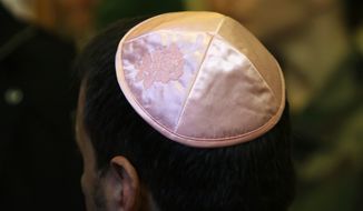 A Jewish man wears his traditional skull cap with an embroidered rose, during a visit of the Interior Minister Bernard Cazeneuve,  at the synagogue, in Marseille, southern France, Thursday, Jan. 14, 2016. A leading Jewish authority in Marseille asked fellow Jews on Tuesday to refrain from  to stay safe after a machete-wielding teen attacked a Jewish teacher. (AP Photo/Claude Paris)