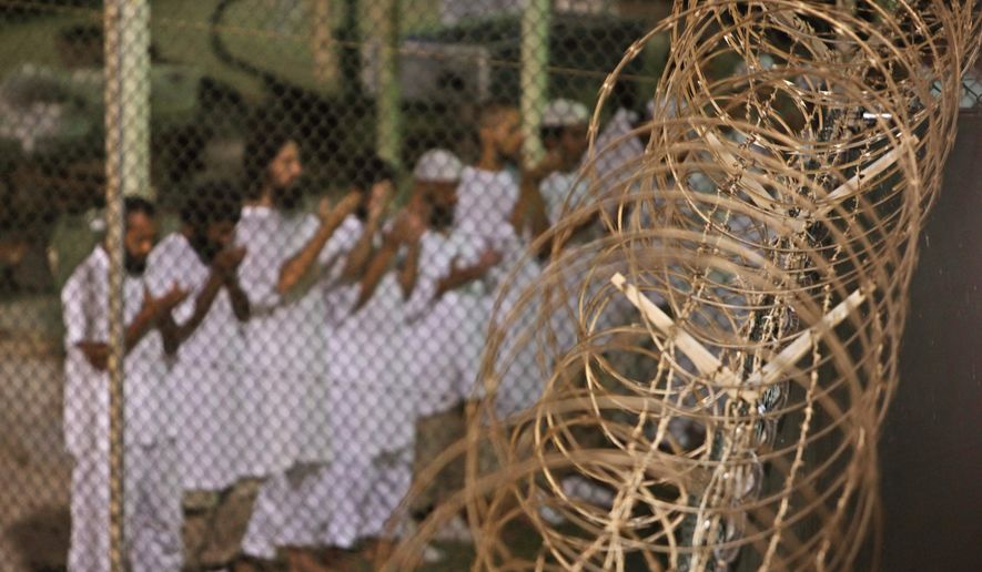 Guantanamo detainees pray before dawn near a fence of razor-wire, inside Camp 4 detention facility at Guantanamo Bay U.S. Naval Base, Cuba, in this May 14, 2009, photo reviewed by the U.S. military. (Associated Press) **FILE**