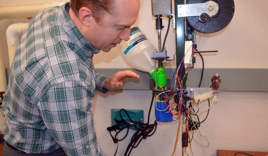 ADVANCE FOR MONDAY, JAN. 18 AND THEREAFTER- In a photo from Jan. 6, 2016, Michigan Technological University associate professor Joshua Pearce explains the operation of the prototype 3-D printer filament maker his students are making in Houghton, Mich. His students are developing a device called a recyclebot, which will use shredded or pelletized waste plastic to make the printer filament. (Kurt Haughlie/The Daily Mining Gazette via AP) MANDATORY CREDIT