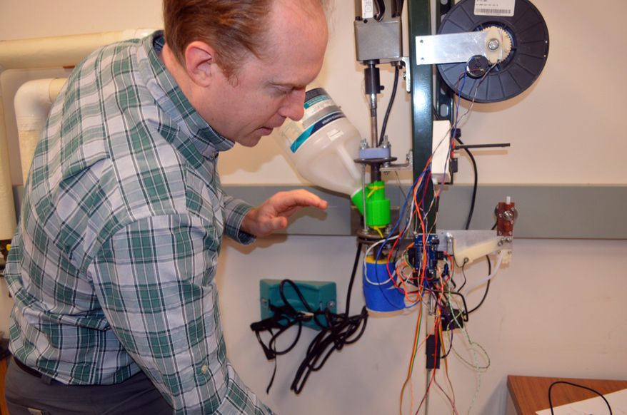 ADVANCE FOR MONDAY, JAN. 18 AND THEREAFTER- In a photo from Jan. 6, 2016, Michigan Technological University associate professor Joshua Pearce explains the operation of the prototype 3-D printer filament maker his students are making in Houghton, Mich. His students are developing a device called a recyclebot, which will use shredded or pelletized waste plastic to make the printer filament. (Kurt Haughlie/The Daily Mining Gazette via AP) MANDATORY CREDIT