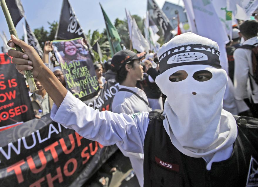 In this June 18, 2014, file photo, a man wears a headband showing the Islamic State group's symbol during a protest calling for the closure of a local prostitution complex in Surabaya, Indonesia. Experts say it is difficult to know how much of a foothold the Islamic State group has established in Indonesia. But the bombing attack at a Starbucks cafe on Thursday, Jan. 14, 2016, achieved two things: Showing that domestic militants, who’ve been besieged and fragmented by a concerted counter-terrorism campaign, are still capable of attacks, and suggesting that the Islamic State group has expanded its ability to launch attacks in Southeast Asia for the first time. (AP Photo/Dita Alangkara, File)