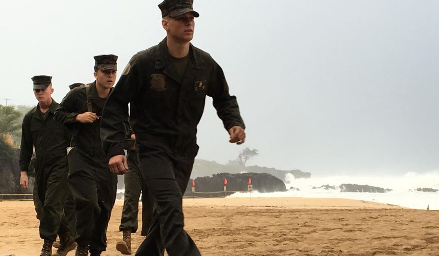 U.S. Marines walk on the beach at Waimea Bay near Haleiwa, Hawaii, where two military helicopters crashed into the ocean about 2 miles offshore, Friday, Jan. 15, 2016. The helicopters carrying 12 crew members collided off the Hawaiian island of Oahu during a nighttime training mission, and rescuers are searching a debris field in choppy waters Friday, military officials said. (Mariana Keller via AP Photo)