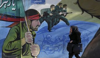 An Iranian woman walks past a mural depicting Iranian armed forces in the battlefield, at Palestine Sq. in Tehran on Jan. 16, 2016. (Associated Press) **FILE**