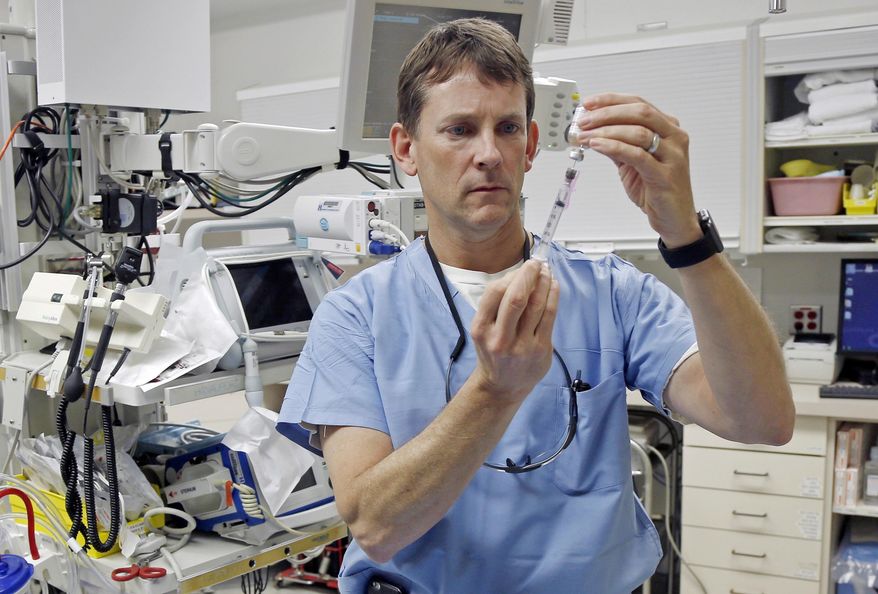 In this Jan. 14, 2016 photo, Dr. John Hick, a Hennepin County Medical Center emergency physician and a national expert in disaster planning, demonstrates preparation of an injection at the Hennepin County Medical Center in Minneapolis. At the prodding of the federal government, state health departments nationwide are hurrying to complete "Crisis Standards of Care" plans to guide medical professionals in such catastrophes and determine what should trigger them. (AP Photo/Jim Mone)