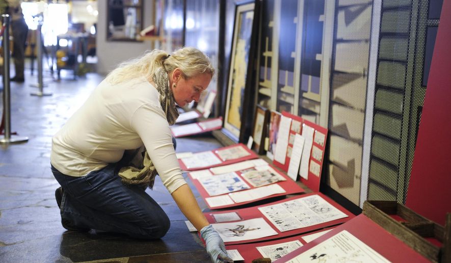 In this Friday, Jan. 15, 2016 photo, Montana Historical Society curator Amanda Streeter Trum adds I.D. tags to pieces in the upcoming exhibition on the work of Montana cartoonist Stan Lynde in Helena, Mont. "From the Heart: Stan Lynde's Comic Creations," will open Thursday, Jan. 21 at the historical society. (Thom Bridge/Independent Record via AP) MANDATORY CREDIT