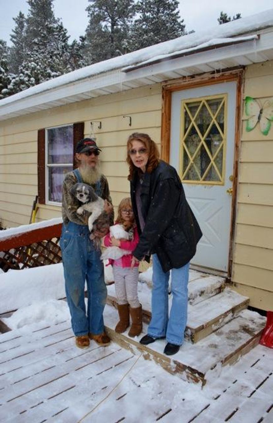 In a Friday, Jan. 15, 2016 photo, Mike and Debra Martzand Debra Martz stand with their grandaughter Avyona Keiry, 5, on the front porch of their Maitland Road home in Central City, S.D., where one of their dogs was killed by a mountain lion. The couple is warning neighbors of the “aggressive lion.” (Mark Watson/Black Hills Pioneer via AP)