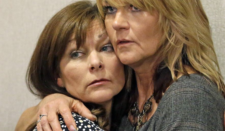 FILE - This Sept. 19, 2014, file photo, Susan Hunt, left, is hugged by her sister, Cynthia Moss, during a news conference, in Salt Lake City. A Utah judge heard arguments Tuesday, Jan. 19, 2016, on whether Susan Hunt, the mother of Darrien Hunt, who was fatally shot by police while holding a samurai sword, should have to accept a $900,000 settlement from the city that employs the officers. (AP Photo/Rick Bowmer, File)
